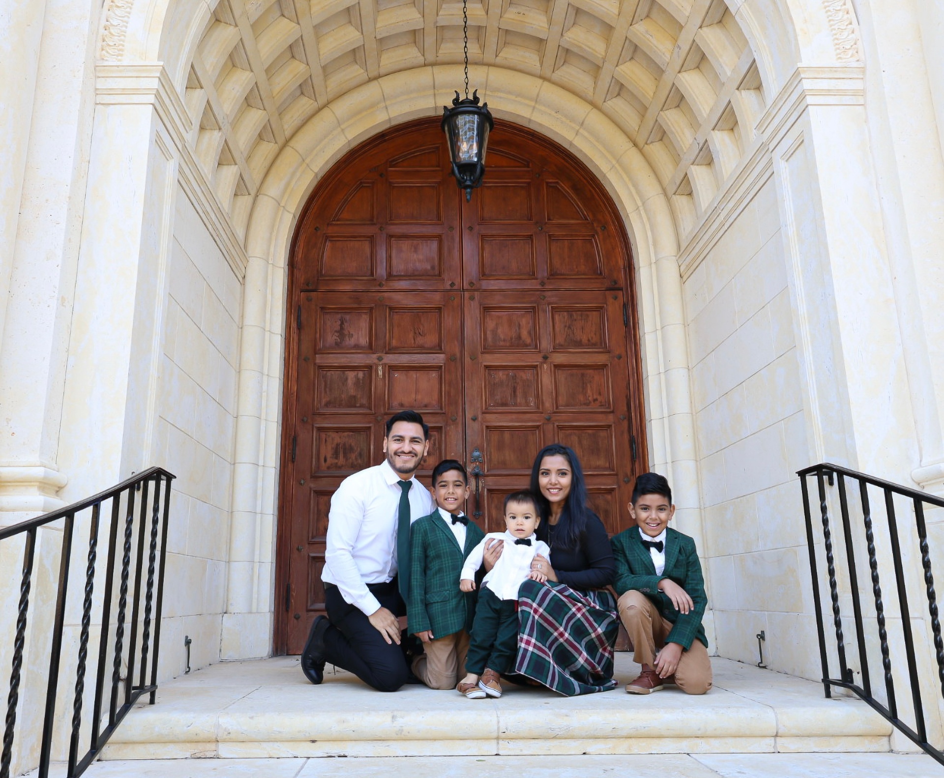 Eddie with his wife and three of their four sons on stone steps beneath an arched doorway.